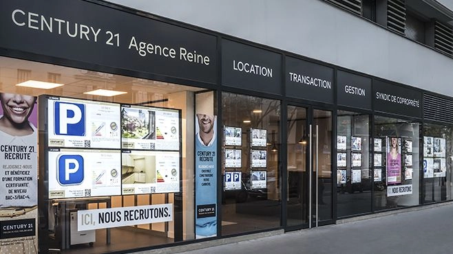 Zdjęcie przedstawia witrynę agencji nieruchomości, która wykorzystuje nowoczesne systemy linkowe LED do ekspozycji materiałów reklamowych. Podświetlane kieszenie zawieszone na stalowych linkach prezentują oferty mieszkań oraz informacje dodatkowe, dzięki czemu całość jest dobrze widoczna, profesjonalna i elegancka nawet w słabszych warunkach oświetleniowych.